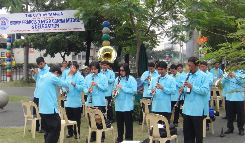 Manila barangay band serenading Japanese pilgrims with Filipino music.